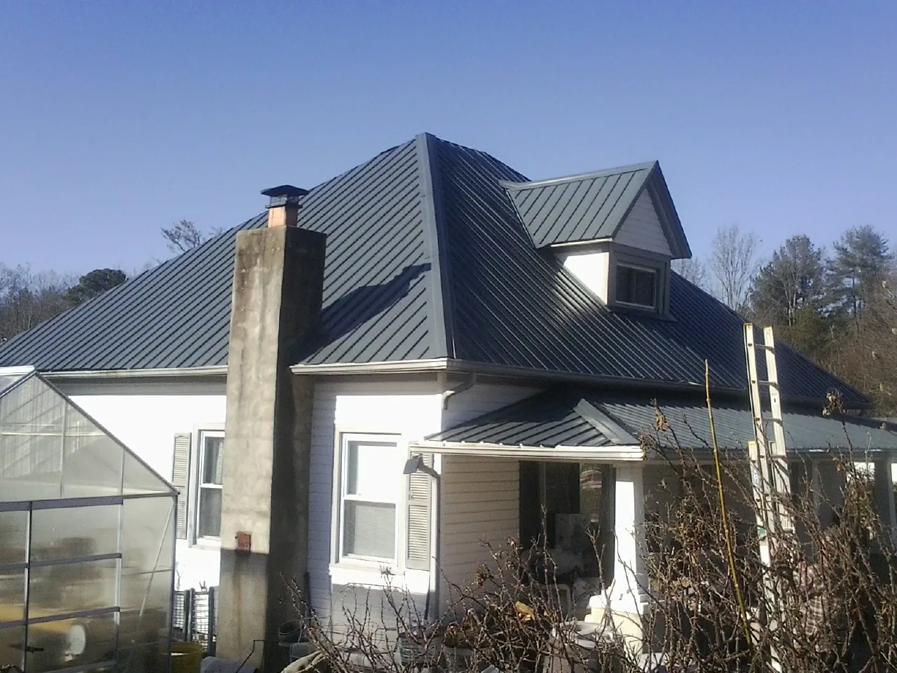 Dark blue standing seam metal roof on a white farmhouse with dormer — Slate & Tile Roof Repair by Roofing Brothers in Steep Falls
