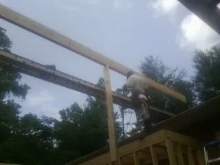 Carpenter setting a ridge beam over a new addition frame — Ice Dam Removal by Roofing Brothers in Steep Falls