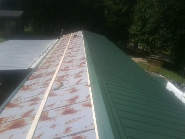 Old rusted panels beside newly installed green metal roofing — Wind Damage Roof Repair by Roofing Brothers in Steep Falls