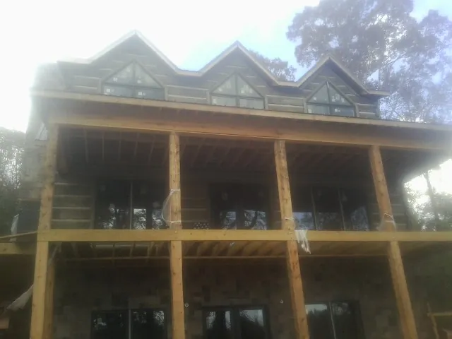 Dormers and porch framing on a large log home under construction — Roof Coating work by our crew in Steep Falls