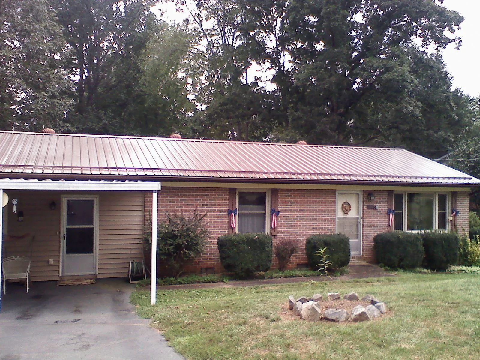 Bronze metal roof and carport on a brick ranch home — Roof Repair work by our crew in Steep Falls