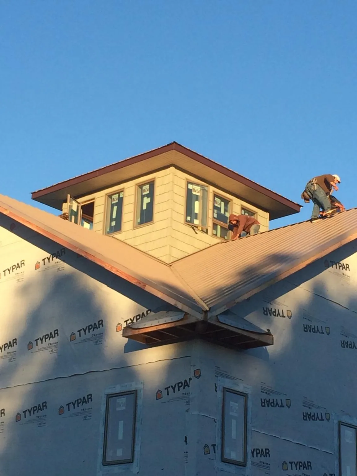 Roofers working around a rooftop cupola on a new metal roof at sunset — Roof Waterproofing in Steep Falls by Roofing Brothers